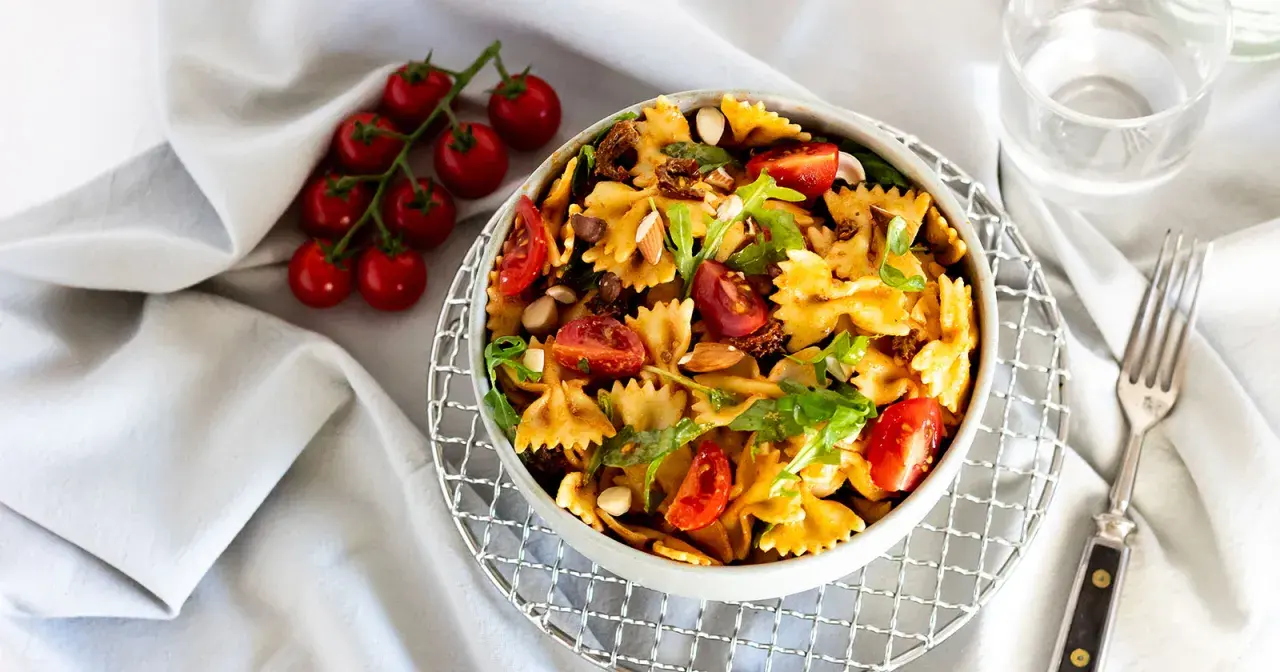 Mediterraner Salat mit getrockneten Tomaten und Rucola, garniert mit Mandeln und frischen Kirschtomaten. Ein köstliches Gericht.