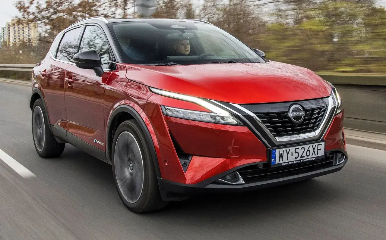 Czerwony Nissan Qashqai 2022 z napędem e-POWER pędzi po drodze, ukazując swoje nowoczesne linie i światła LED.