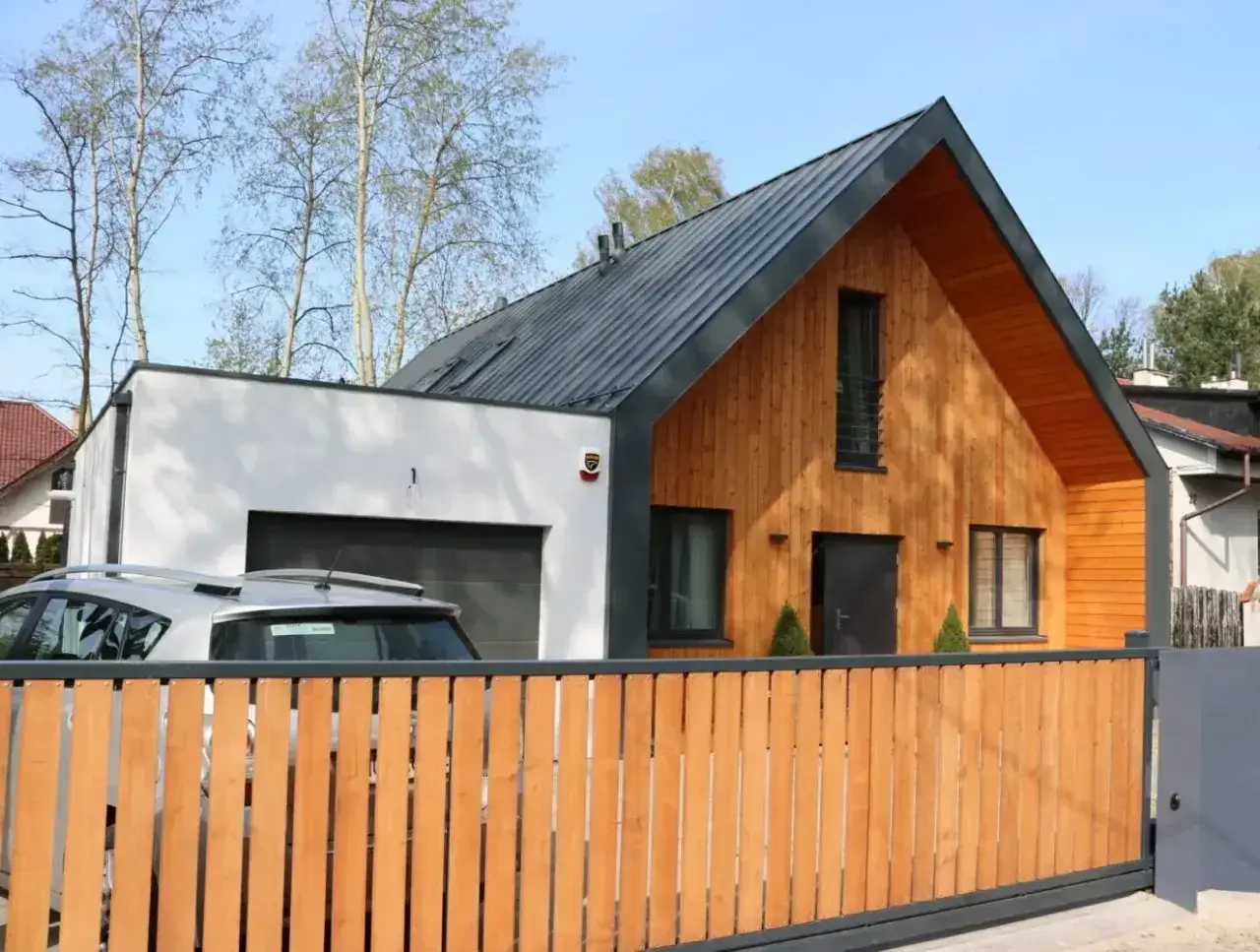 Nowoczesna dobudówka do starego domu, z drewnianą elewacją i garażem. Projekty architektoniczne łączące tradycję z nowoczesnością.