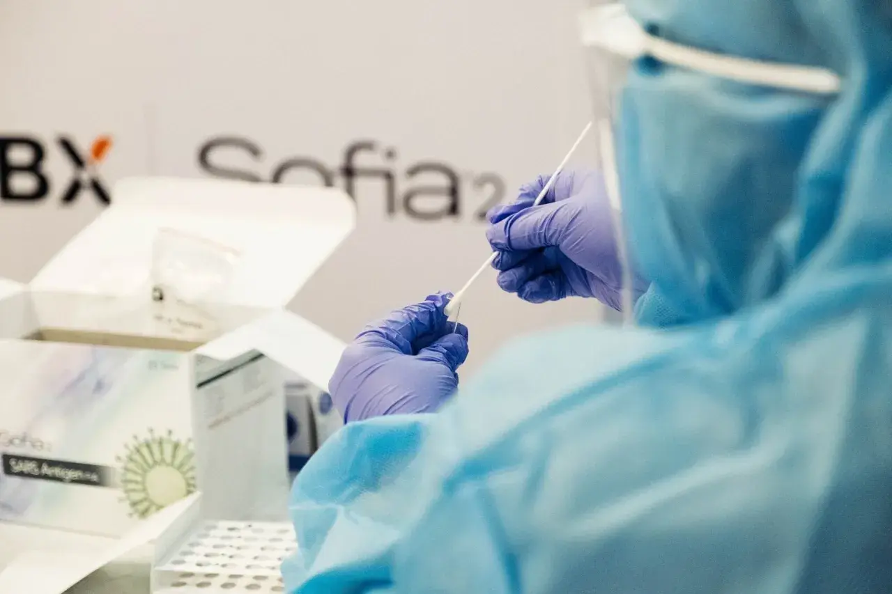 Osoba w kombinezonie i rękawiczkach przygotowuje testy Sofia SARS Antigen. To ważny kurs, który pomaga w diagnostyce.