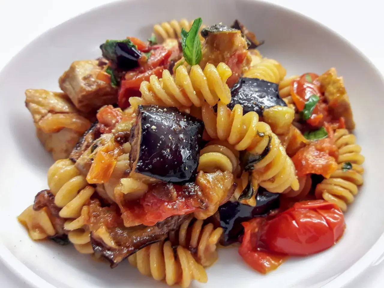 Fusilli con pesce spada, melanzane, pomodorini e basilico, un piatto estivo saporito.
