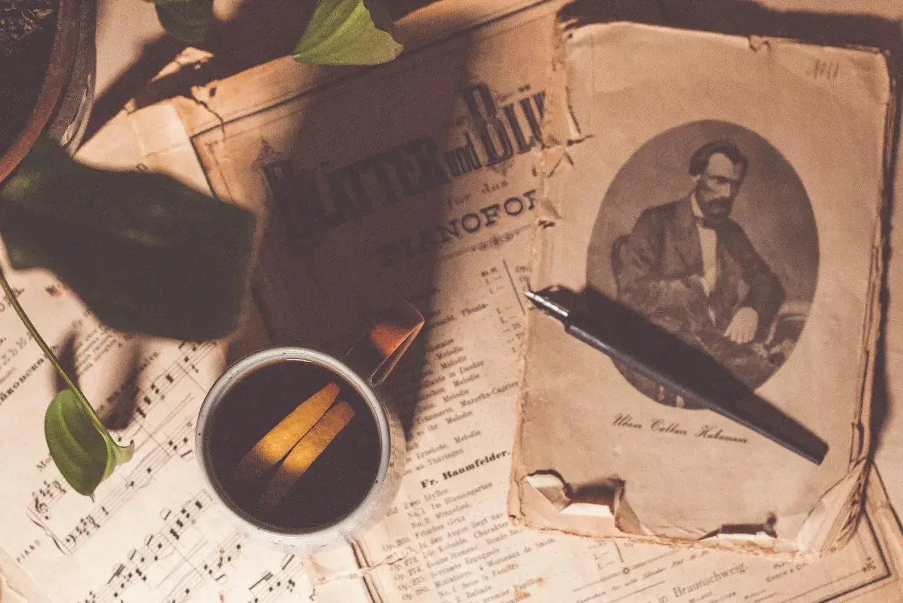 Sepia fotografia. Stare nuty, filiżanka kawy z pomarańczą i pióro.