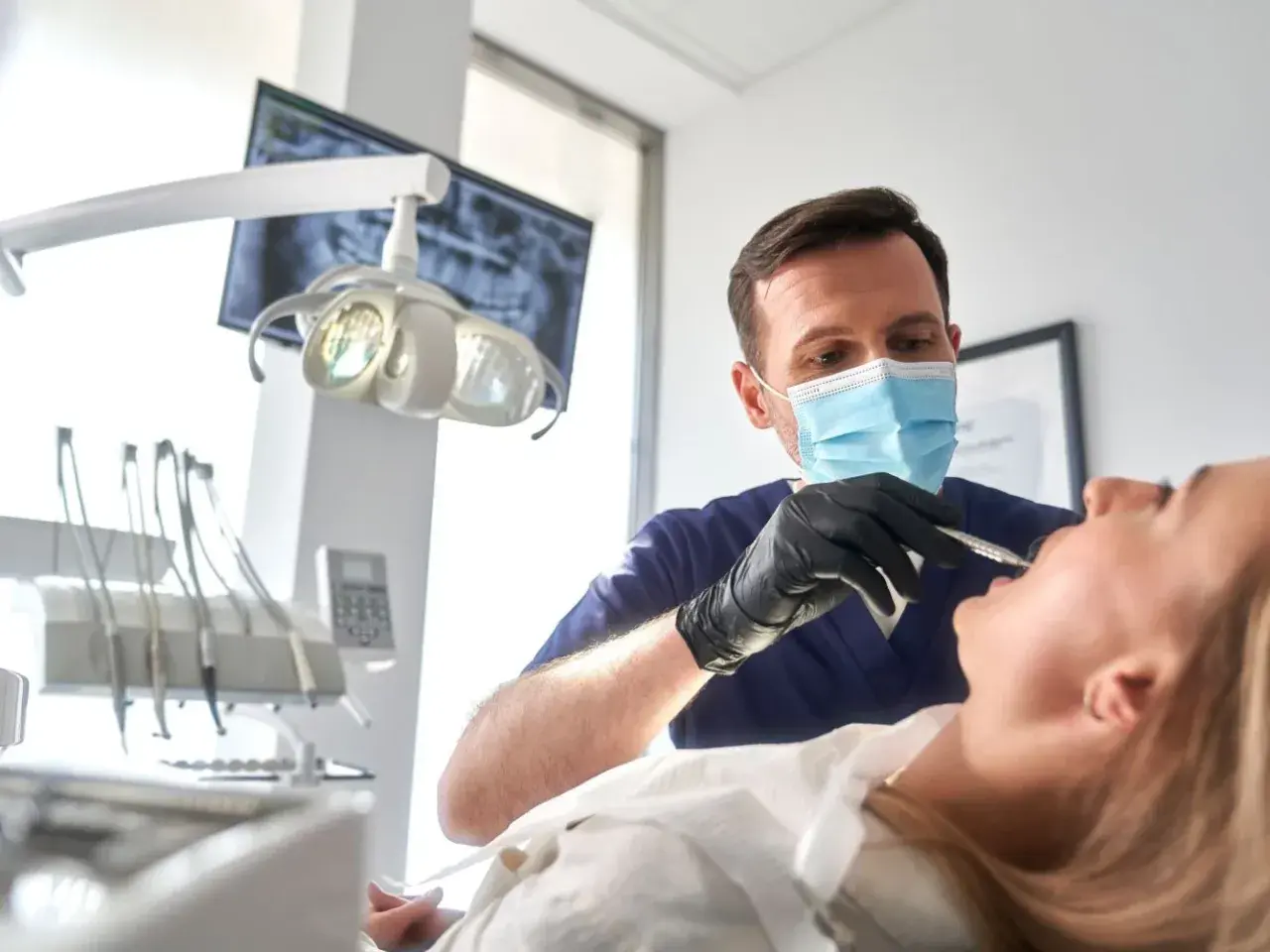 Dentista esamina un paziente, con un occhio attento alla salute orale. Un sorriso sano vale più di un bonus dentista 500 euro.