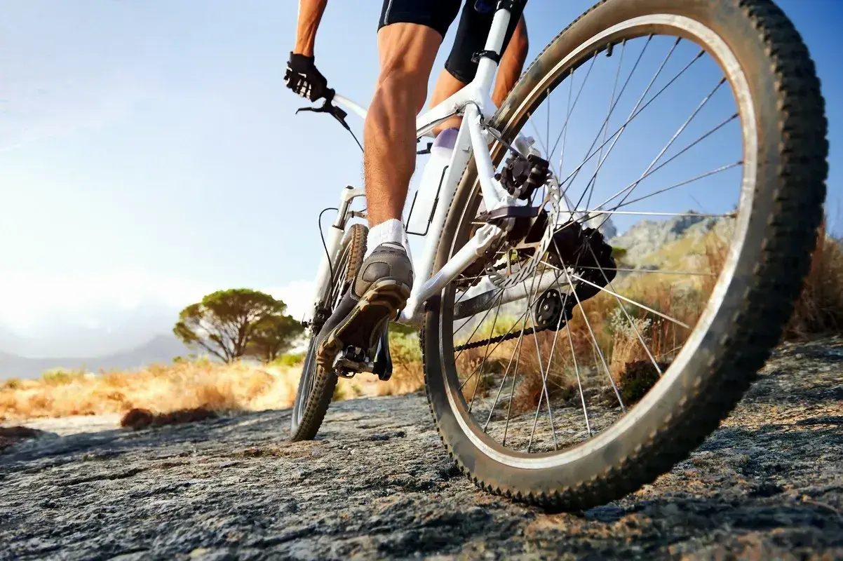 Rowerzysta na rowerze crossowym lub trekkingowym pokonuje kamienisty szlak.