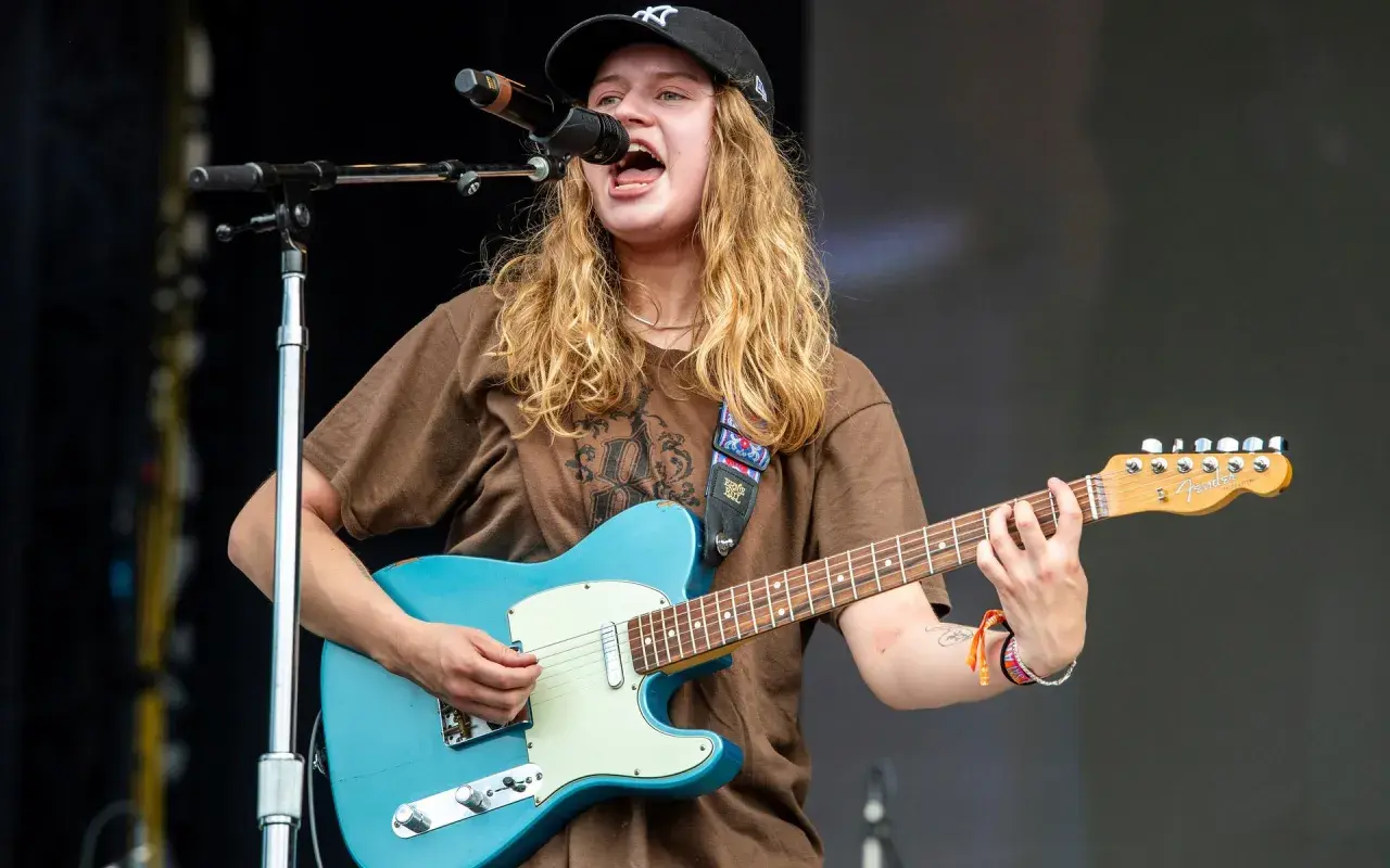 Mona på scen, sjunger och spelar gitarr med en blå Fender.