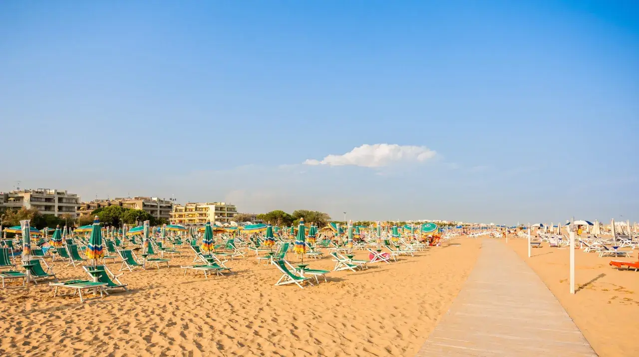 Piękna plaża w Bibione, pełna leżaków i parasoli, zaprasza do relaksu. Liczne atrakcje czekają na turystów.