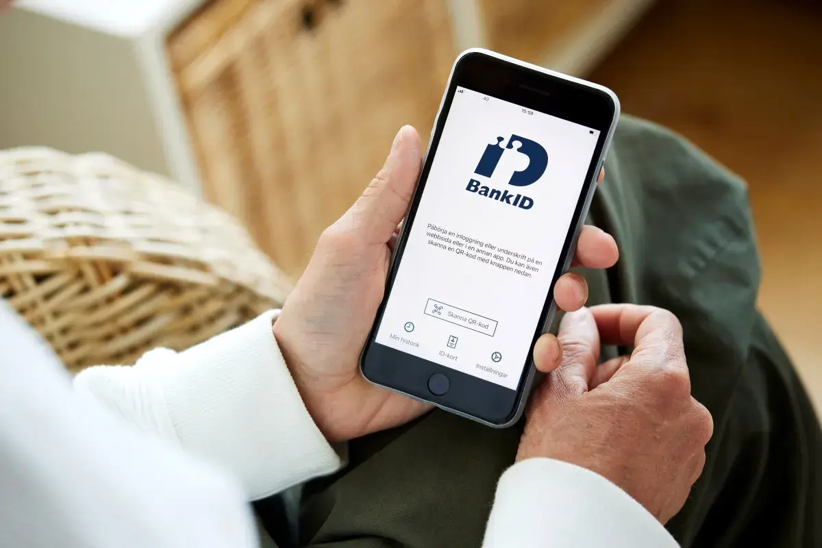 Person håller upp en telefon med BankID-appen öppen, redo för inloggning eller underskrift. Perfekt för din bankID ny telefon.