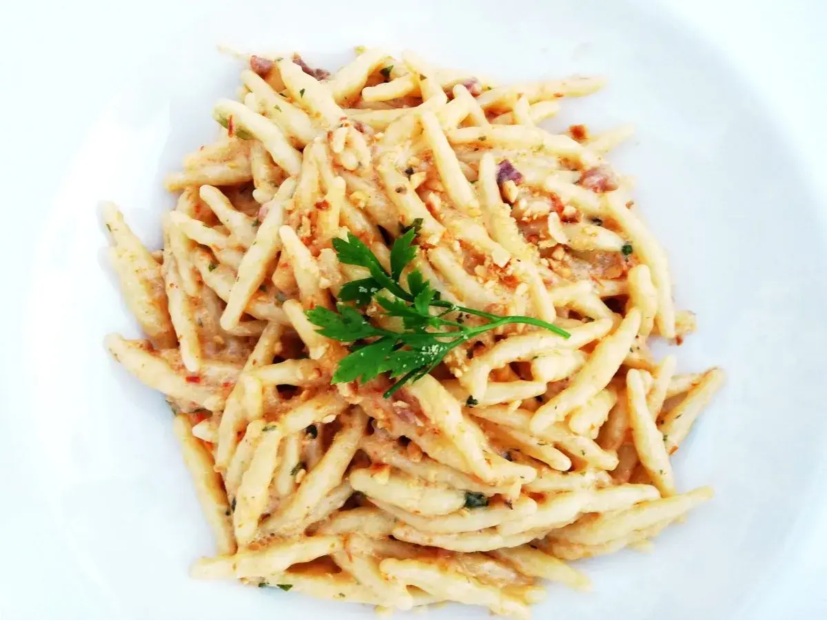 Un piatto di trofie cacio e pepe, condite con una cremosa salsa al formaggio e pepe, guarnite con prezzemolo fresco.