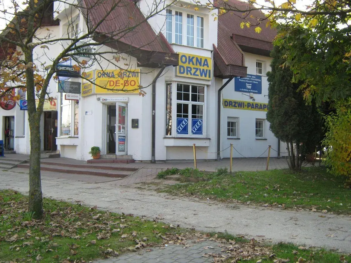 Budynek z żółtymi banerami "OKNA DRZWI" i "DRZWI PARAPETY" w Olsztynie.