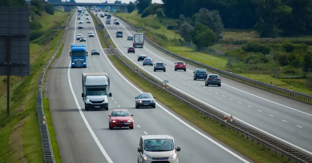Na autostradzie ruch samochodów. Niebieska ciężarówka wykonuje wyprzedzanie z prawej strony, omijając inne pojazdy.