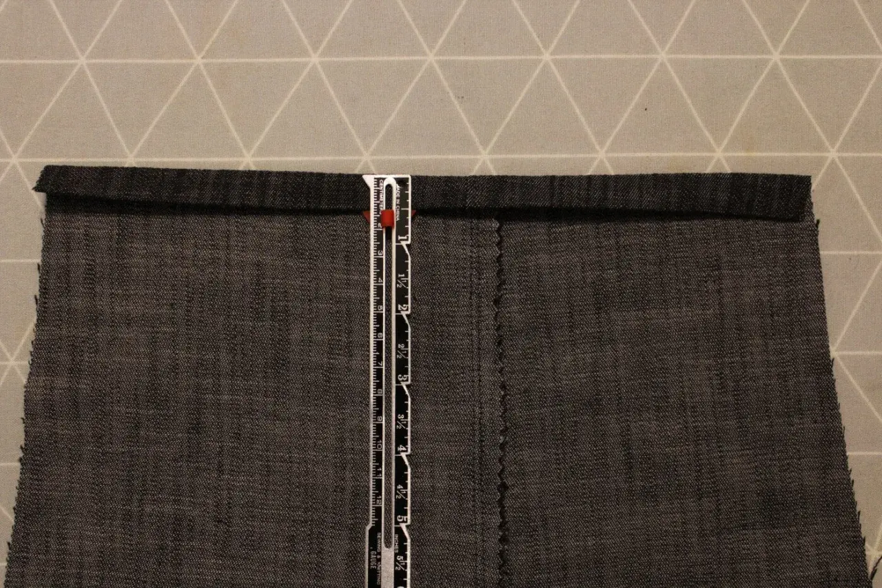 A ruler measures a dark grey cotton twill fabric. The fabric has a visible weave, characteristic of what is cotton twill.