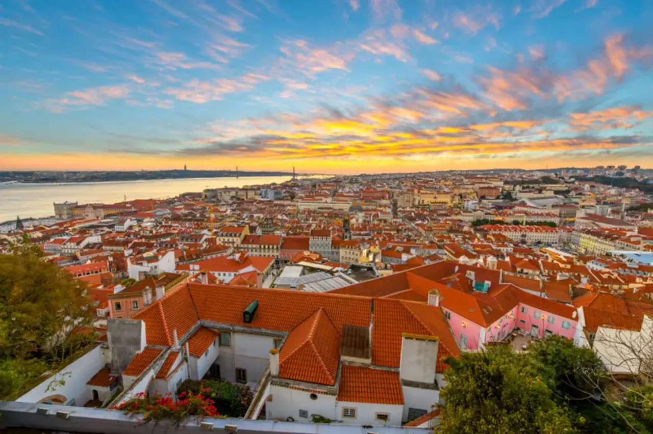 Un espectacular atardecer lisboa baña con tonos dorados y rosados el cielo sobre la ciudad y el río Tajo.