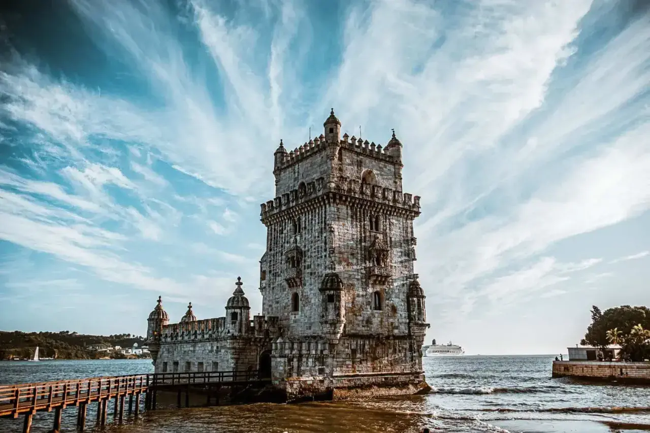 La Tour de Belém, un incontournable pour savoir que faire à Lisbonne, se dresse fièrement sur l'eau sous un ciel spectaculaire.