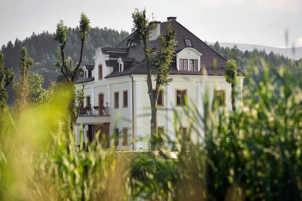 Elegancka restauracja "Kaczka na wodzie" w otoczeniu zieleni, z widokiem na las i wzgórza.