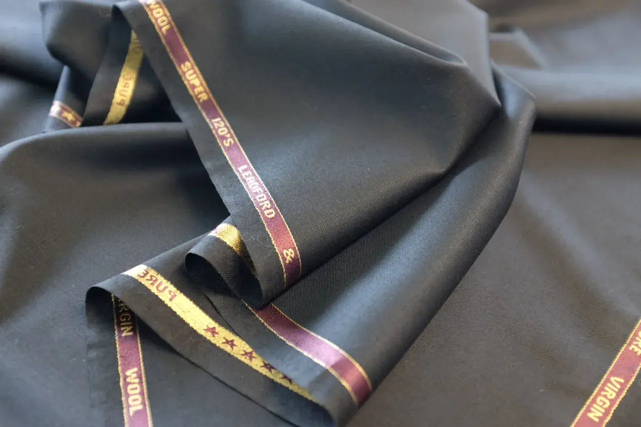 Elegancka, czarna wełna z metką "Super 120's Virgin Wool". Idealna na garnitur.