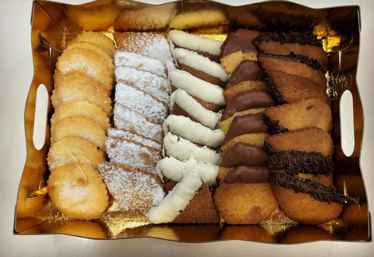 Bandeja dorada con surtido de galletas: almendradas, espolvoreadas con azúcar glas, bañadas en chocolate blanco y negro. ¡La mejor pastelería Zaragoza!