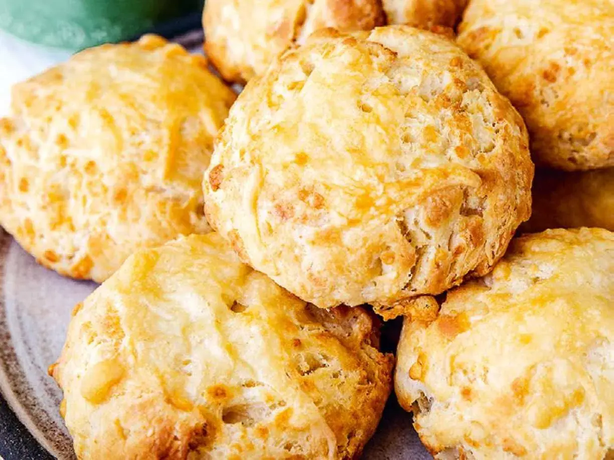 En hög med gyllene, fluffiga ostscones, perfekta för en mysig fika.