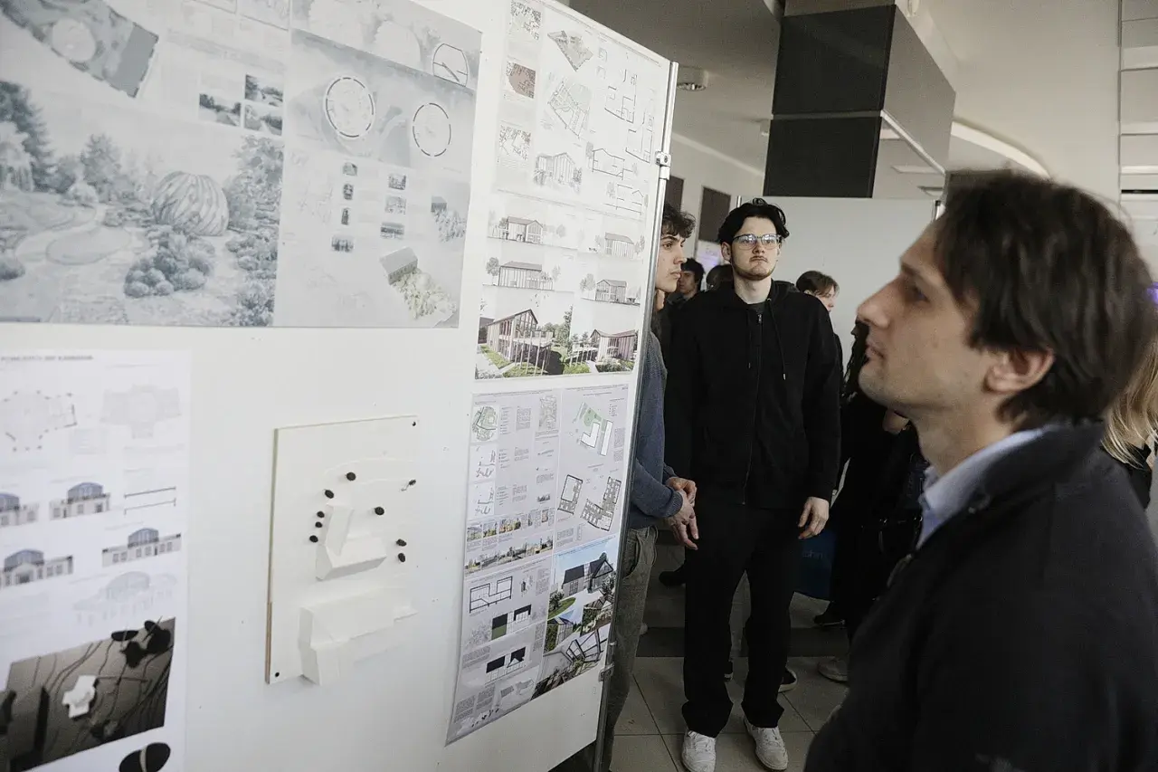 Ludzie oglądają wystawę projektów architektonicznych i makiety budynków.