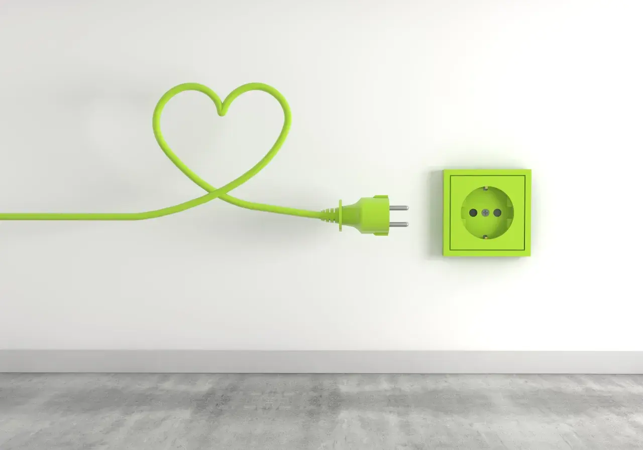 Zielony kabel w kształcie serca podłączony do gniazdka, symbolizujący troskę o niskie opłaty za media.