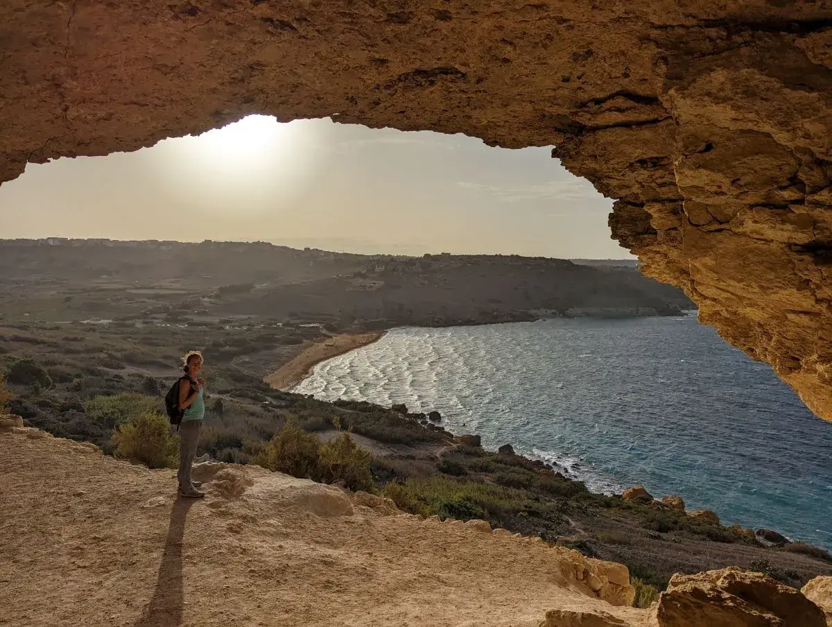 Frauenblick auf die Bucht von Malta im Dezember. Das Wetter ist mild, die Sonne scheint, und die Wellen brechen am Strand.