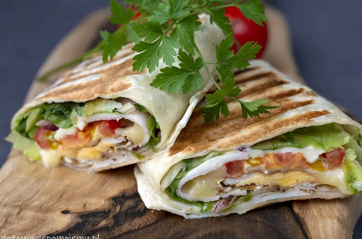 Pyszna tortilla z jajkiem, serem, warzywami i kurczakiem, podana na desce.