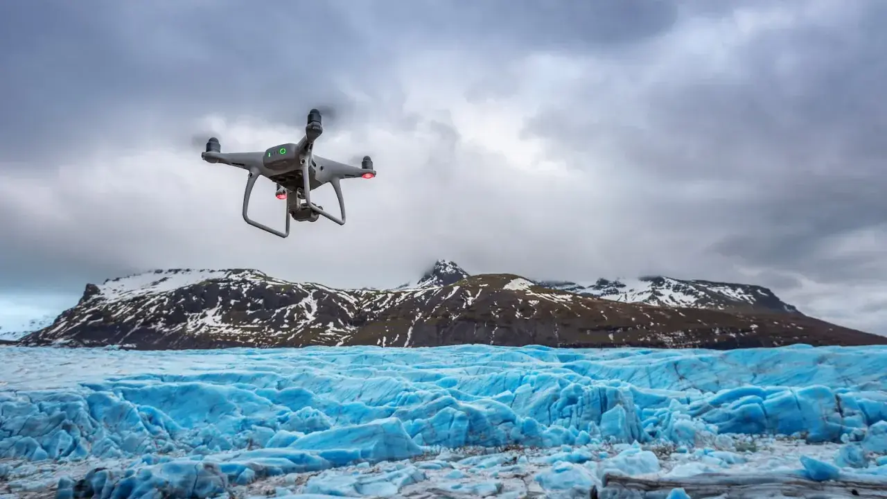 Dron rejestruje spektakularne zdjęcia lodowca o intensywnie niebieskiej barwie, z ośnieżonymi górami w tle.