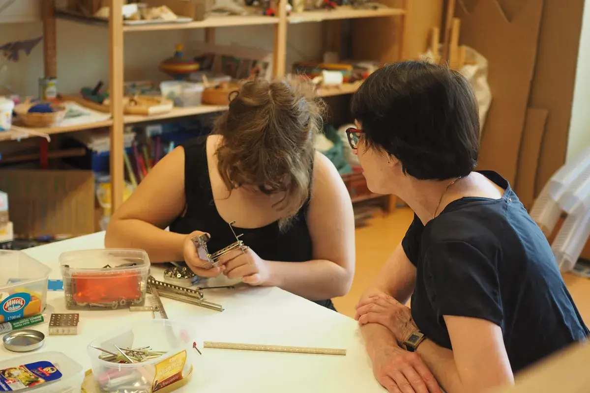 Zwei Frauen arbeiten in einer Lernwerkstatt im Kindergarten. Eine baut mit kleinen Metallteilen.