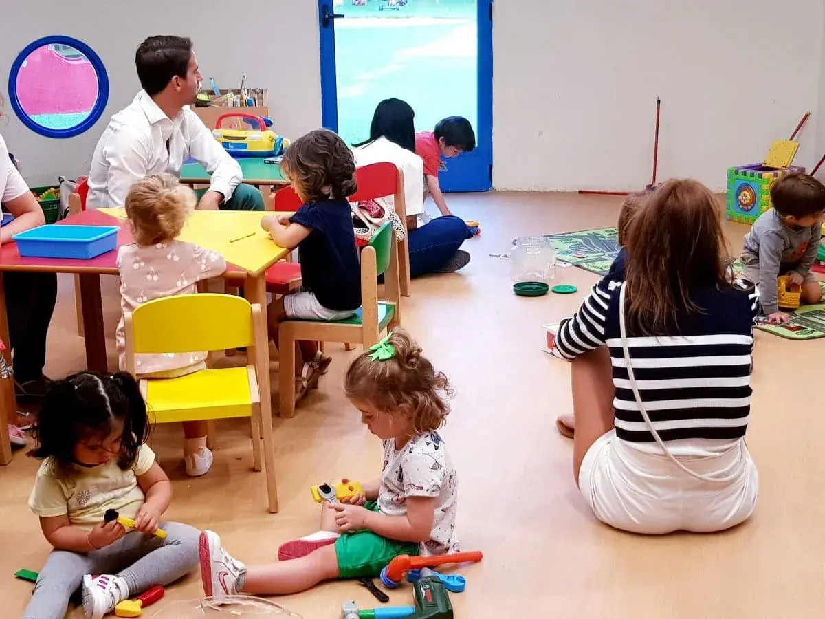 Niños jugando y un adulto observando, parte de lo que es el periodo de adaptación en un aula.
