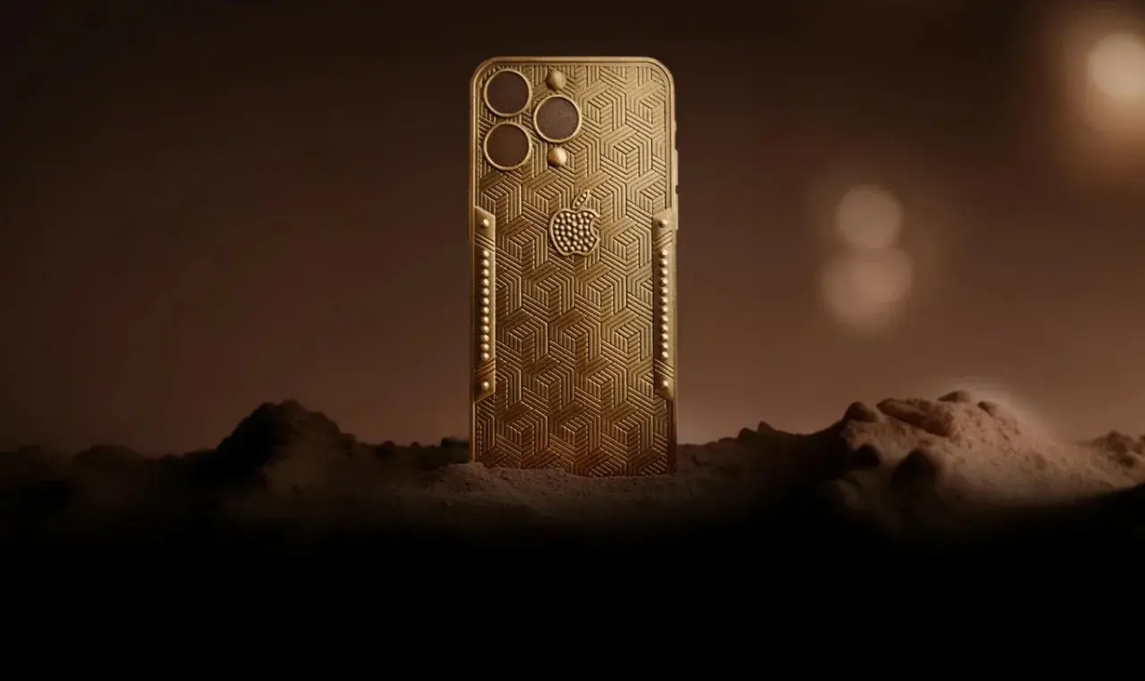 Złoty telefon z wytłoczonym wzorem, przypominający największy telefon na świecie, stoi na tle marsjańskiego krajobrazu.