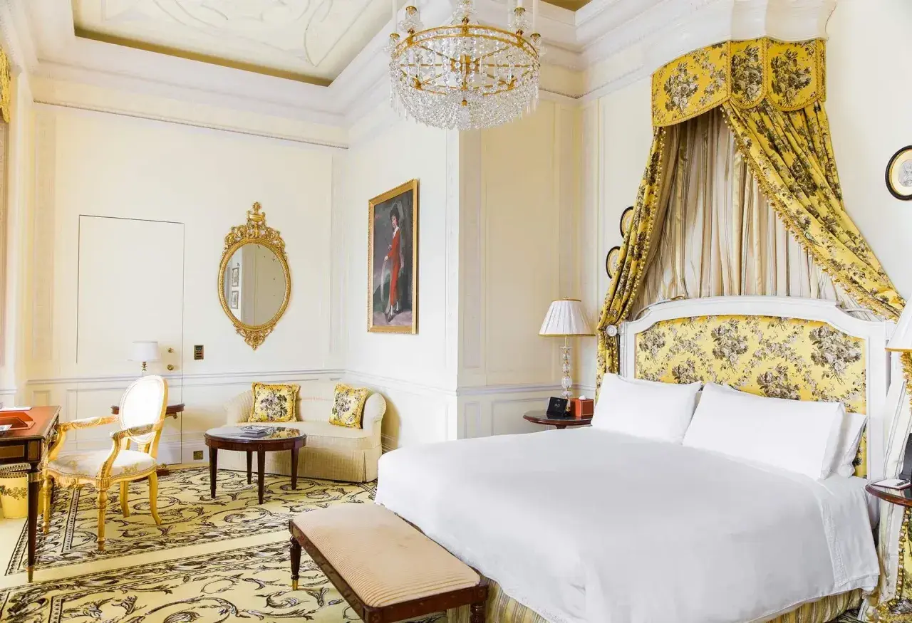 Ett lyxigt hotellrum i London med en stor säng, en sittgrupp och en utsmyckad spegel.