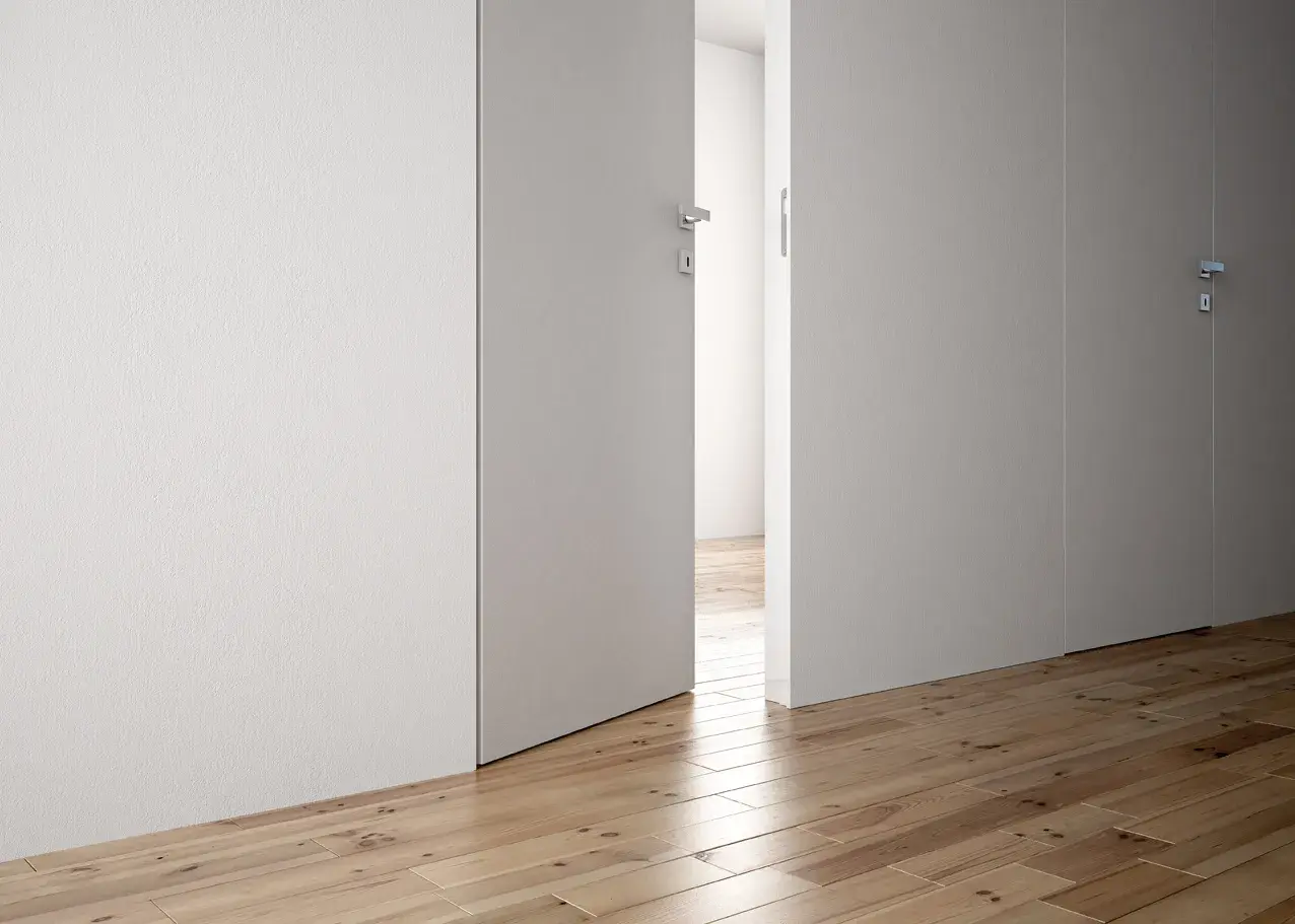 Parete di cartongesso con porta a battente aperta, che rivela un corridoio con parquet.