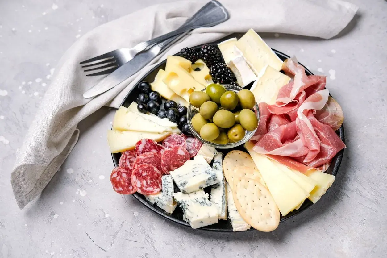 Bei taglieri con salumi, formaggi misti, olive verdi, frutti di bosco e cracker.
