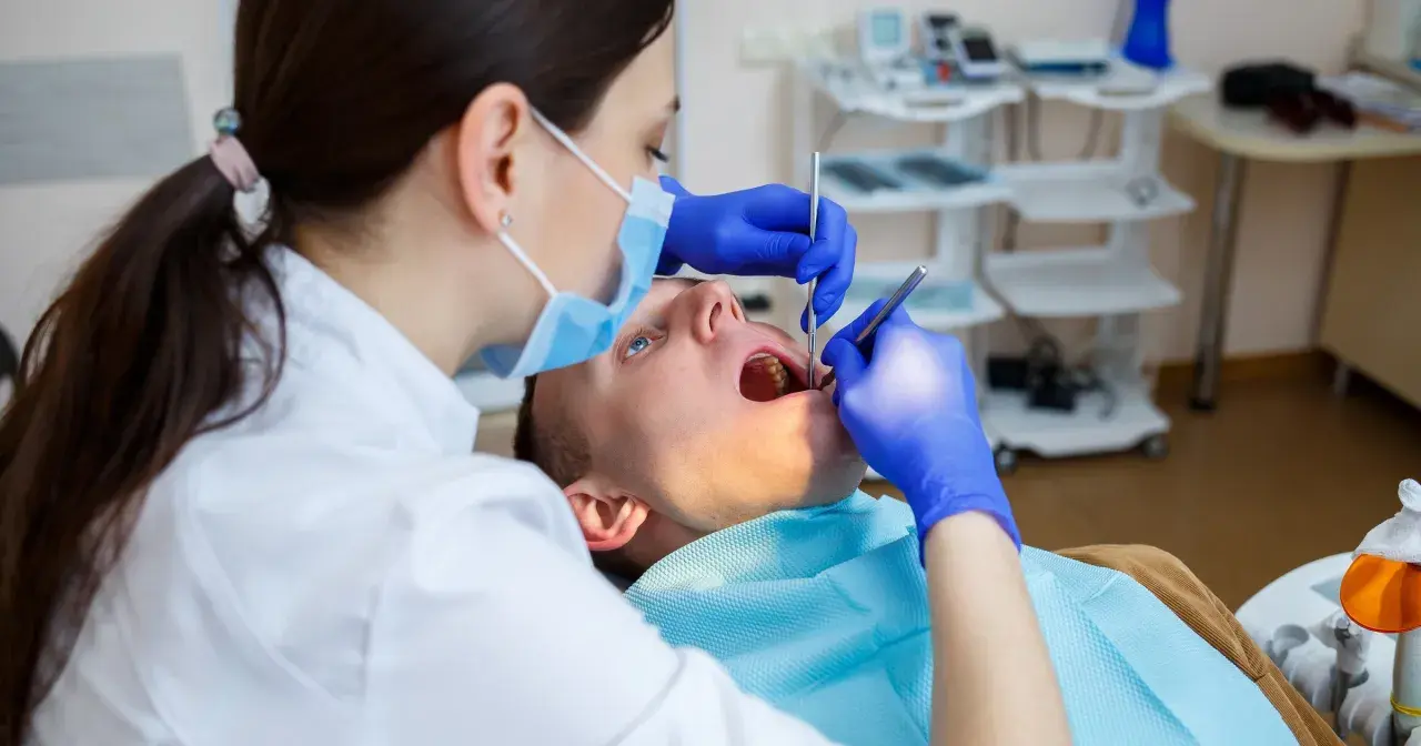 Dentystka bada zęby pacjenta. Zastanawiasz się, na ile dentysta może wystawić L4? Zależy to od stanu zdrowia pacjenta i zaleceń lekarskich.