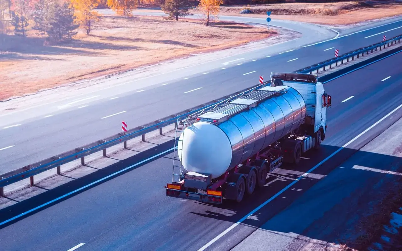Ein Tankwagen transportiert **Gefahrgut ADR** auf einer Autobahn. Der LKW fährt auf der rechten Spur, die Sonne wirft lange Schatten.