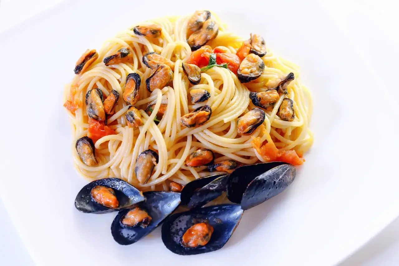 Spaghetti alla tarantina con cozze e pomodorini, un piatto di mare saporito e colorato.