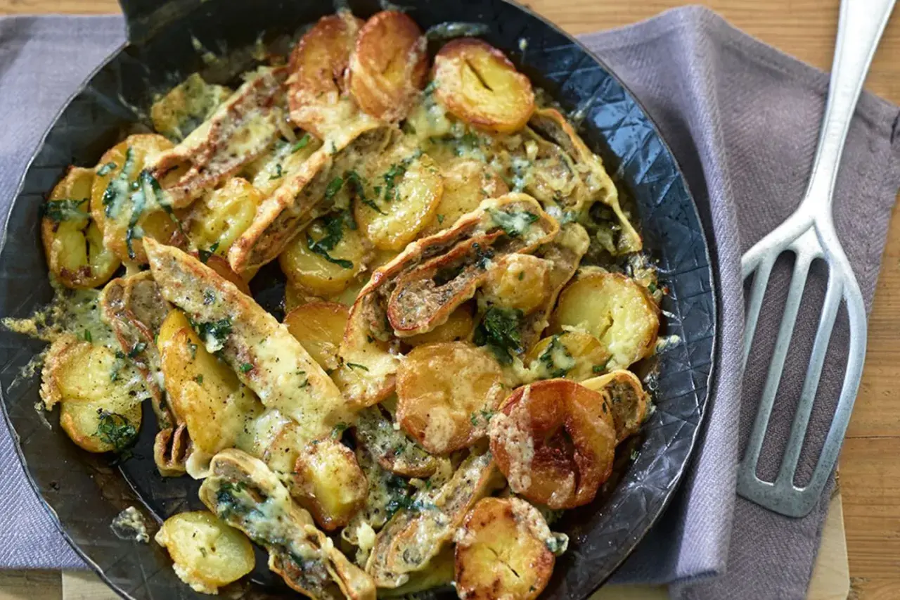 Herzhafte Maultaschen-Pfanne mit goldbraunen Kartoffelscheiben und geschmolzenem Käse, garniert mit frischen Kräutern.