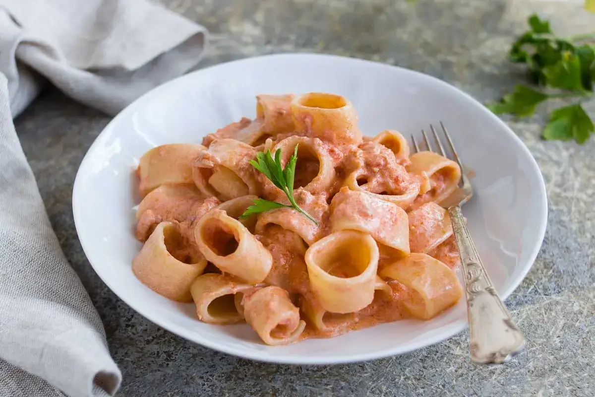 Un piatto di pasta al tonno cremosa, con paccheri conditi e guarniti con prezzemolo fresco.