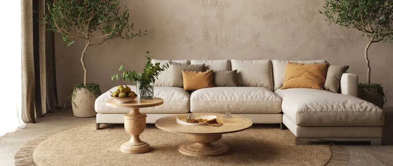Accogliente salotto con divano chiaro, cuscini ocra e verdi, tavolini in legno e piante. Un'atmosfera rilassante con salotto colori caldi.