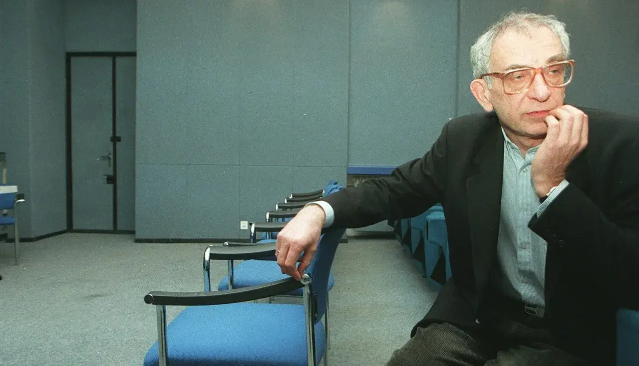 Krzysztof Kieślowski, reżyser znany z głębokich filmów, siedzi w pustej sali.