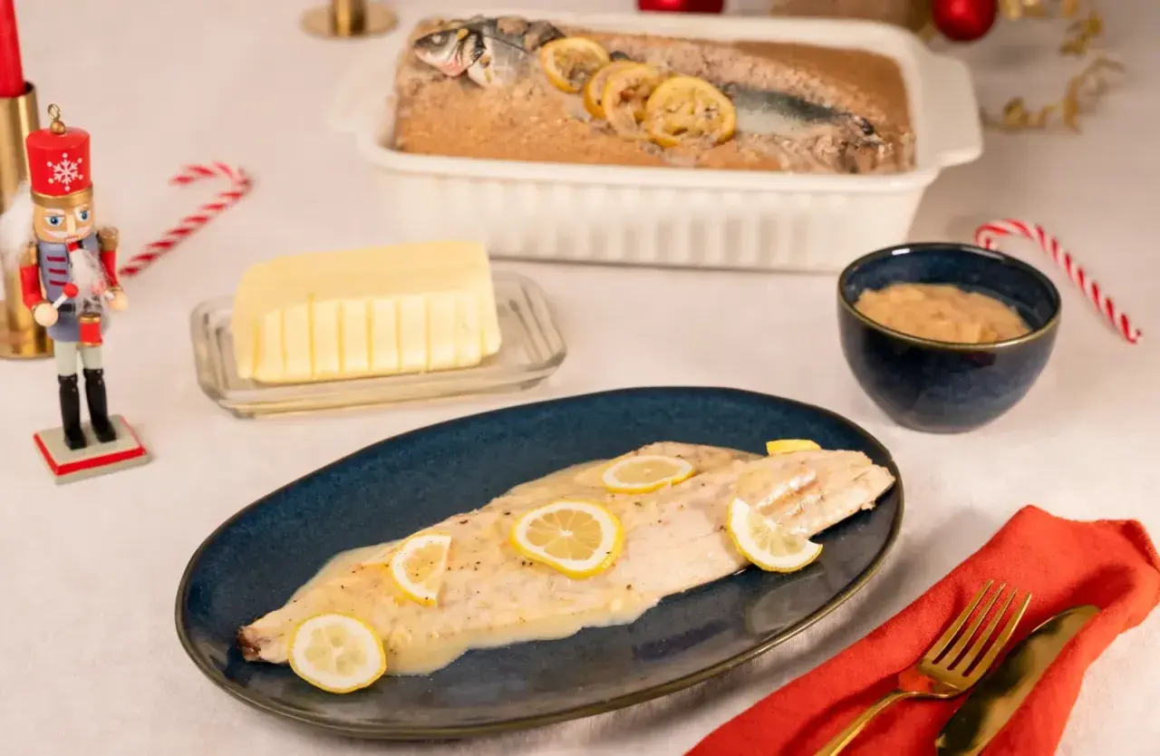 Un bar en croûte de sel, tel que préparé par Julie, est servi avec des rondelles de citron. Un beurre crémeux et une sauce à la moutarde complètent ce plat festif.