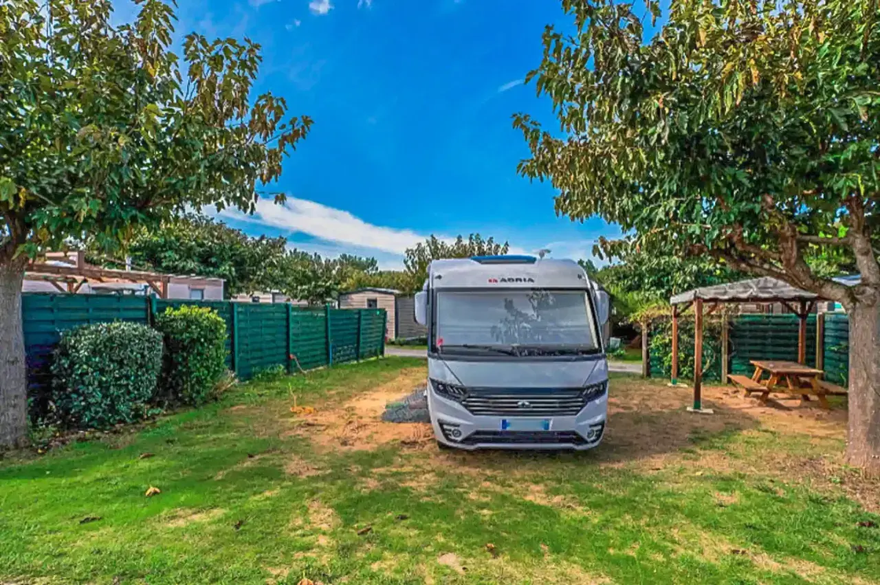 Un camping-car Adria prêt pour l'aventure sur l'Île d'Oléron. Un coin paisible avec pelouse et abri pique-nique.