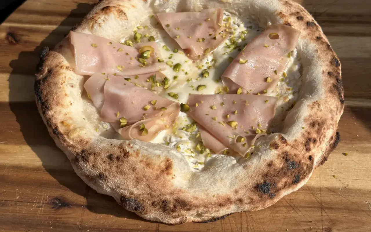 Neapolitanische Pizza mit Mortadella und Pistazien. Die perfekte neapolitanische Pizza Temperatur sorgt für einen luftigen Rand und geschmolzenen Käse.