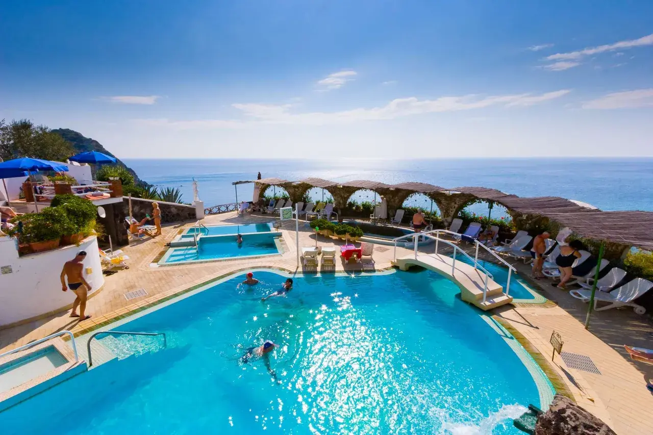 Relax in piscina con vista mare, un sogno a San Valentino Terme. Persone nuotano e si godono il sole.