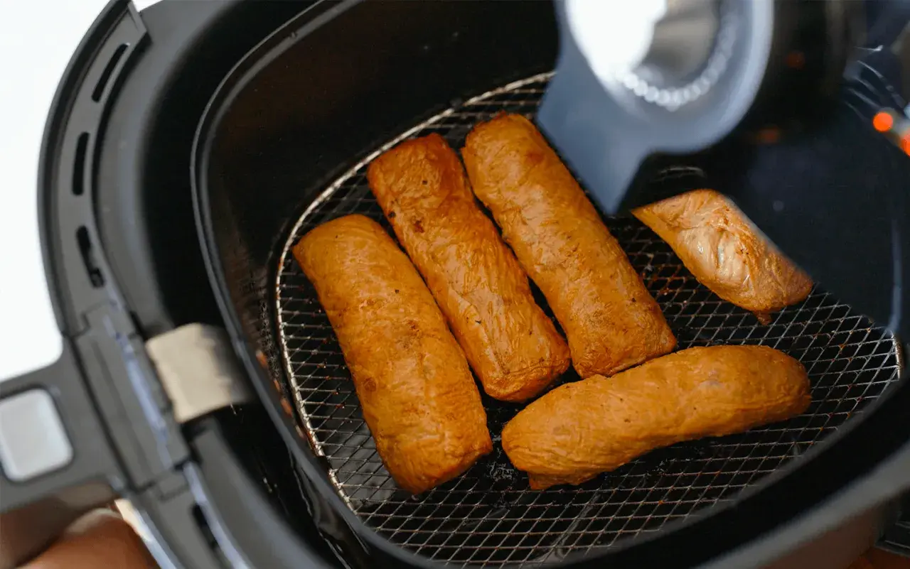 Cinq saucisses dorées dans une friteuse sans huile. Découvrez comment ça marche pour des repas sains et croustillants !