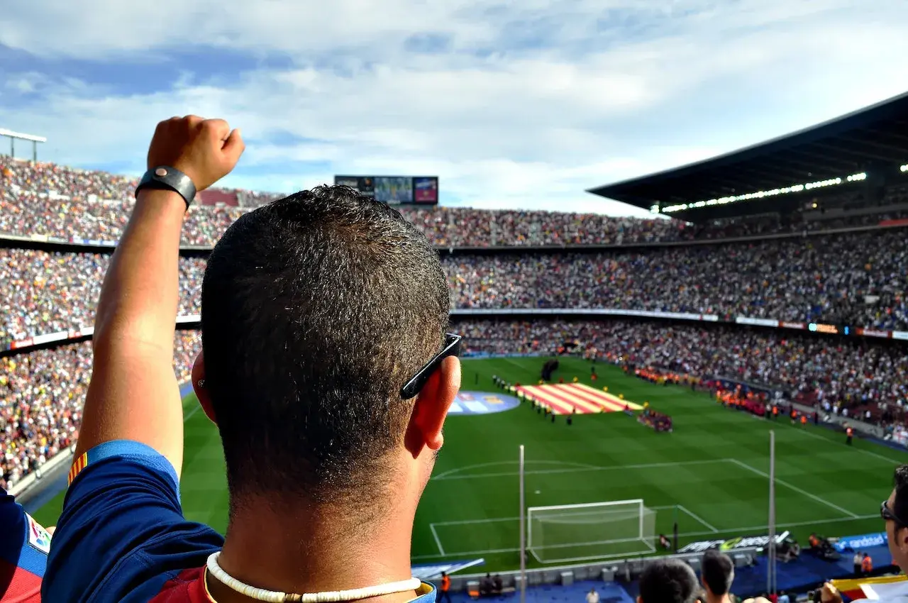 Kibic z podniesioną pięścią na stadionie, dumny jak właściciel Barcelony.