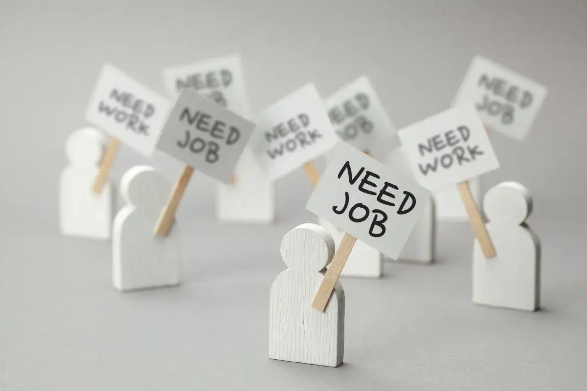 Figurki ludzi z transparentami "NEED JOB" i "NEED WORK". Dowiedz się, jak sprawdzić status bezrobotnego online.