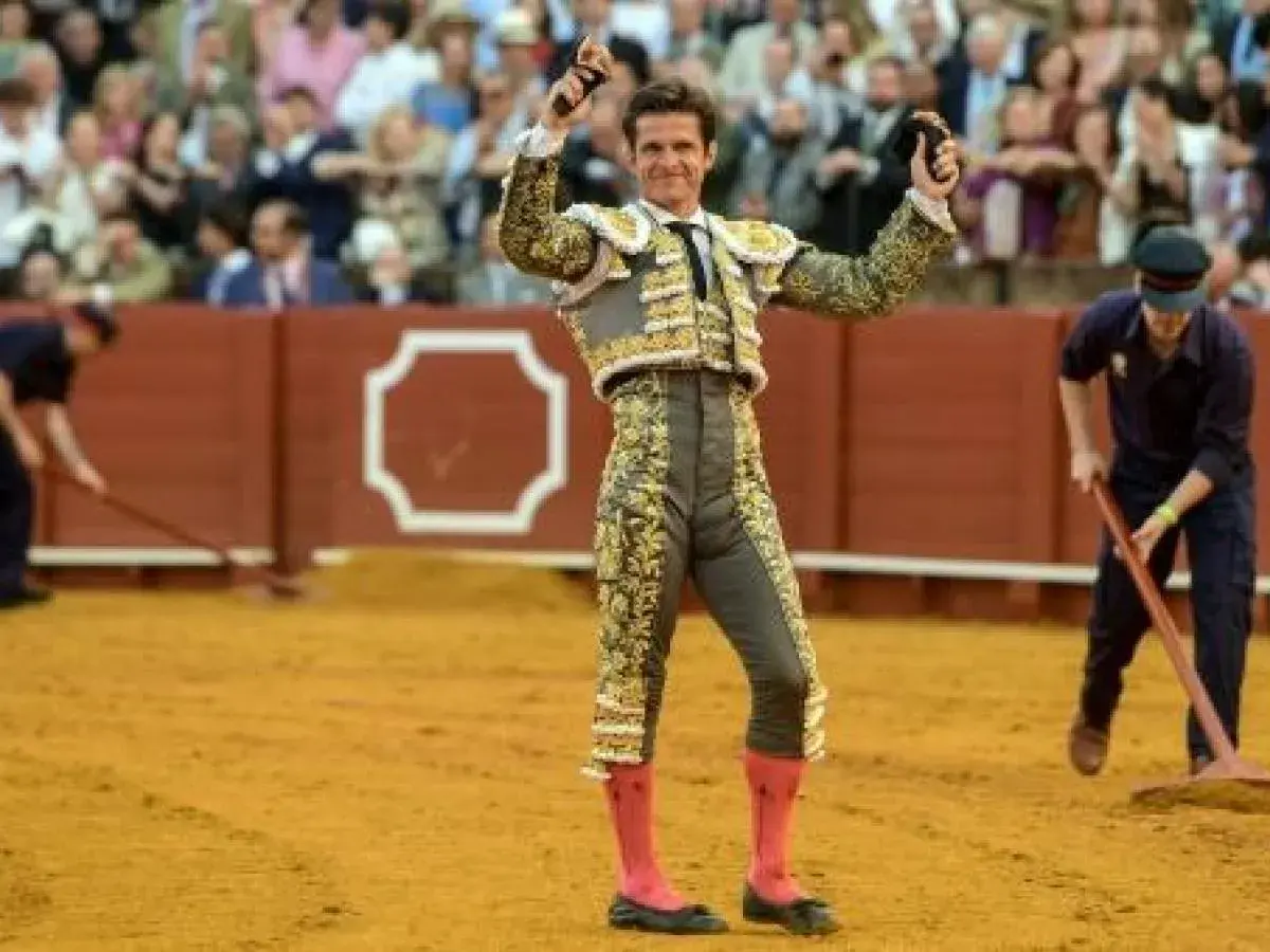 El Juli, torero con traje de luces, levanta las manos en la arena.