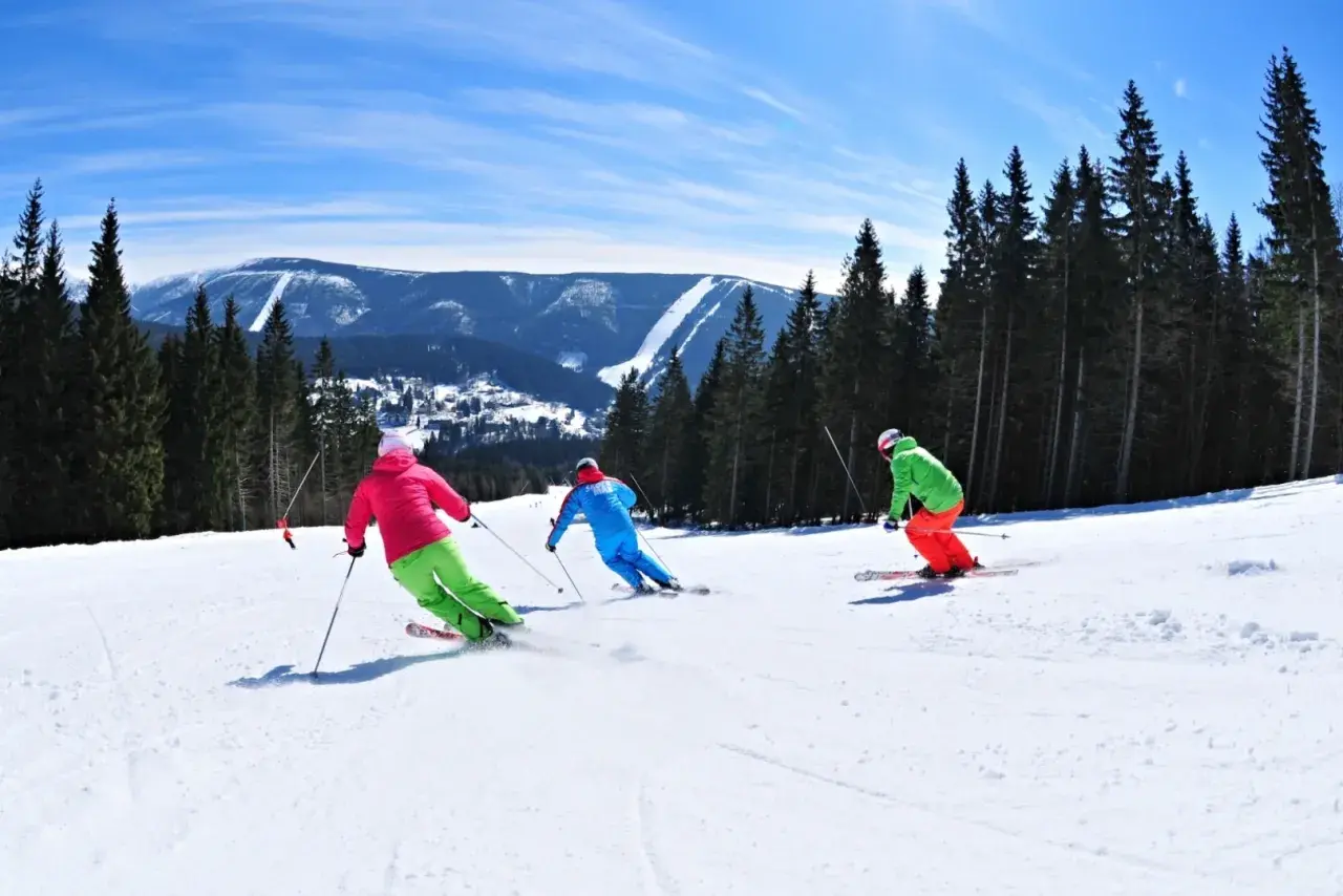 Skifahrer genießen die Pisten in Spindleruv Mlyn. Ein sonniger Tag mit Blick auf die Berge und den Wald.