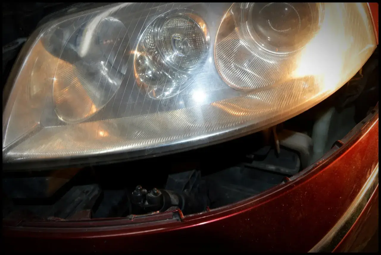 Reflektor Passat B5 FL, widok na żarówki przód. Widać fragment czerwonego lakieru i wnętrze lampy.