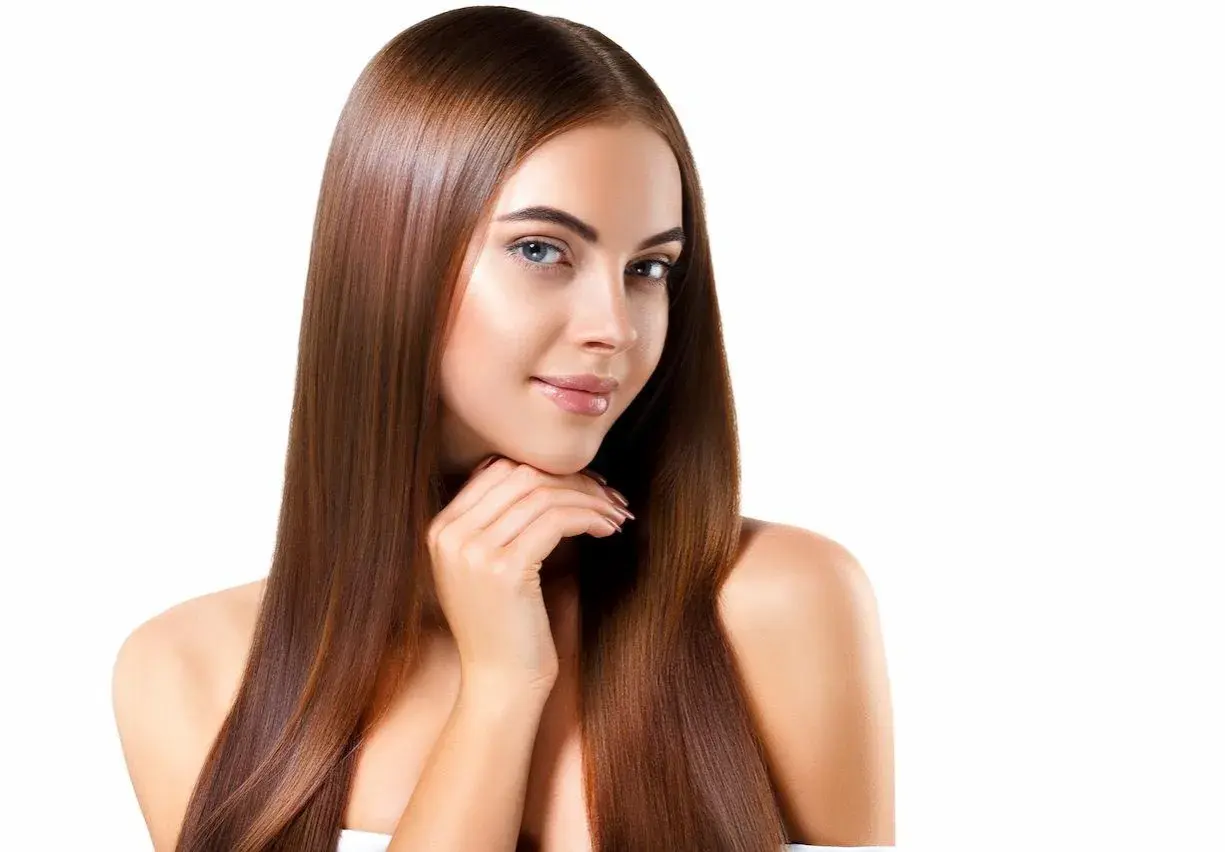 Mujer con cabello largo y liso, color de pelo avellana con reflejos dorados, sonríe suavemente.